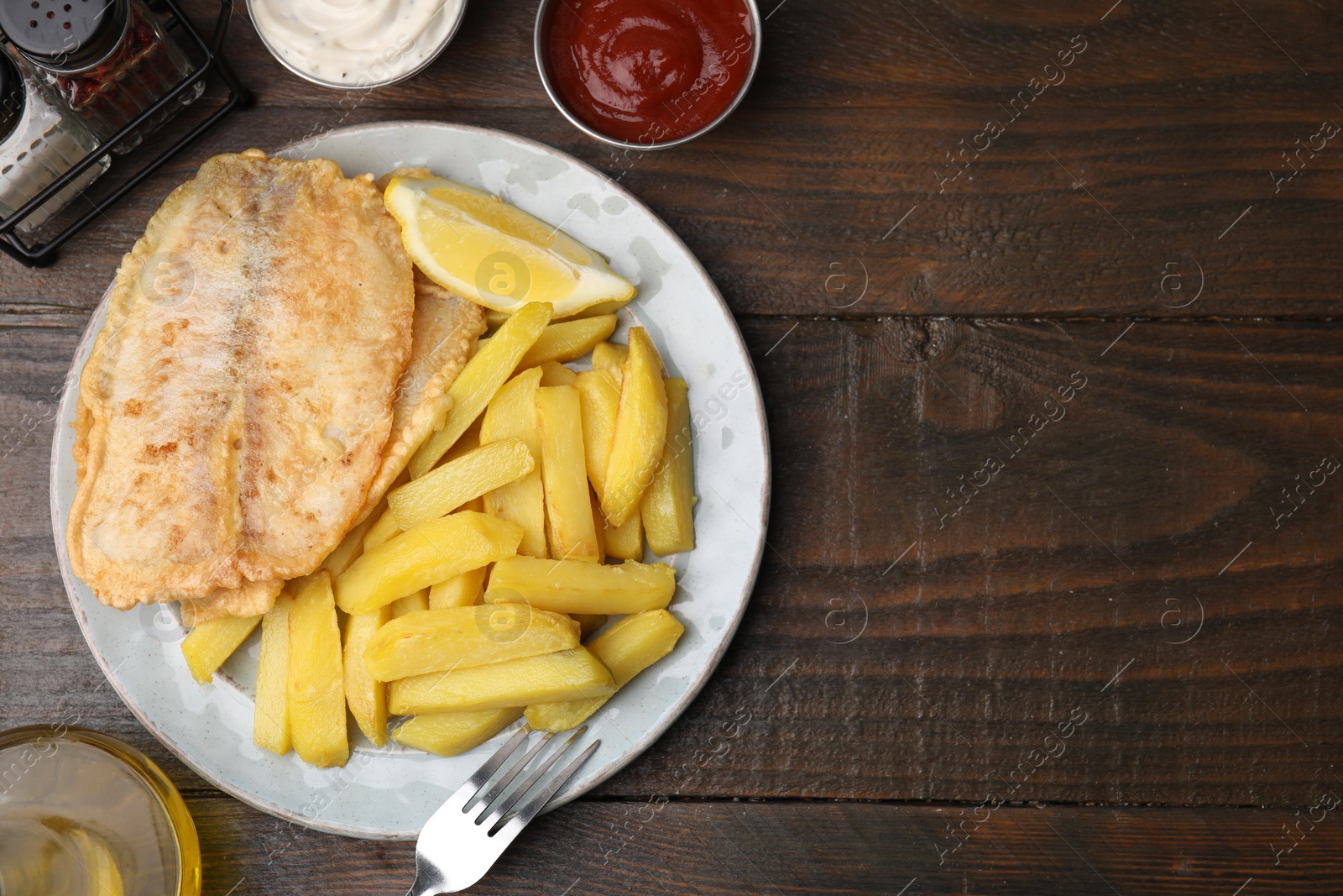 Photo of Delicious fish and chips served on wooden table, flat lay. Space for text