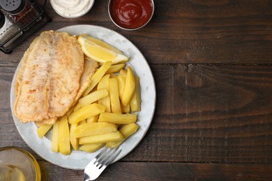 Delicious fish and chips served on wooden table, flat lay. Space for text