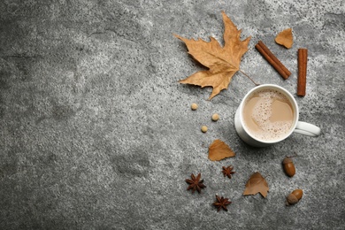 Flat lay composition with cup of hot drink and autumn leaves on grey table, space for text. Cozy atmosphere