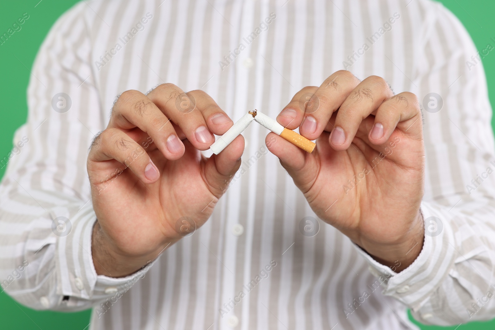 Photo of Stop smoking concept. Man breaking cigarette on green background, closeup