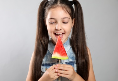 Cute little girl with watermelon on grey background