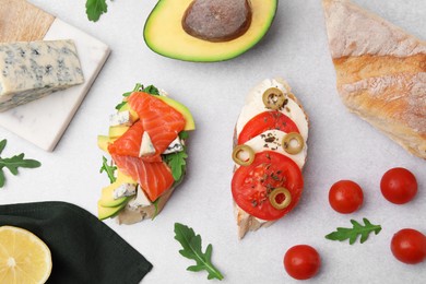 Flat lay composition of different tasty bruschettas and ingredients on light grey textured table