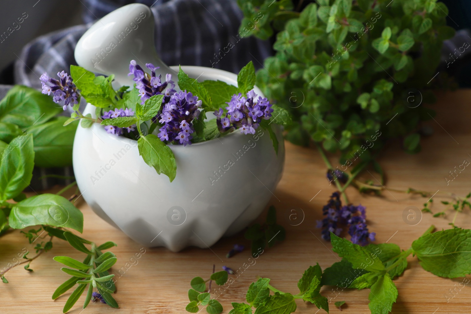 Photo of Mortar with fresh lavender flowers, mint and pestle on wooden table