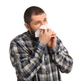 Man with tissue suffering from runny nose on white background