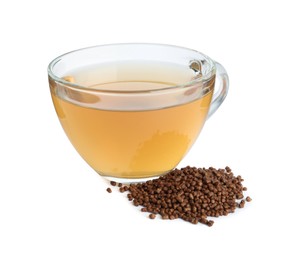 Photo of Glass cup of buckwheat tea and granules on white background