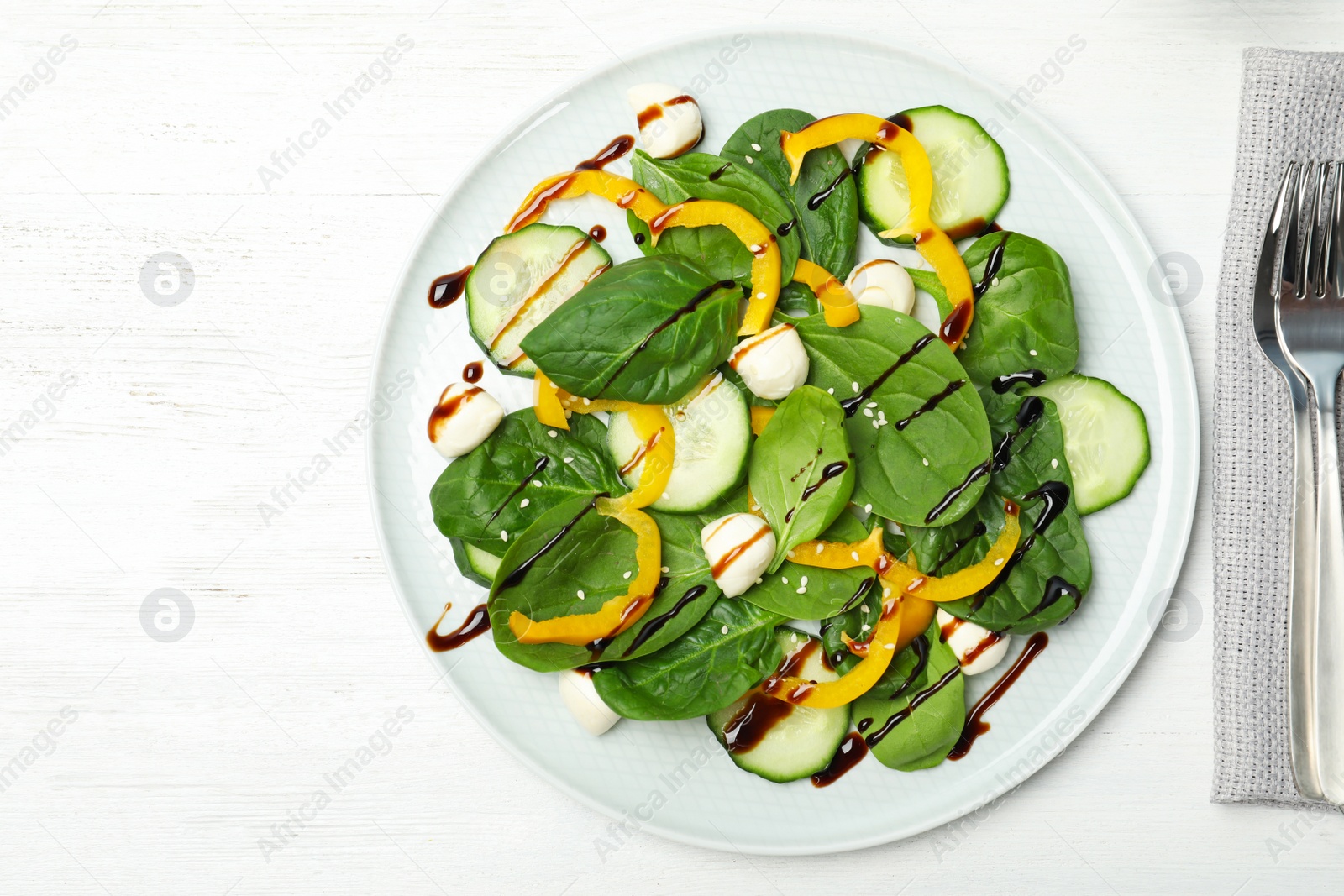 Photo of Fresh vegetable salad with balsamic vinegar served on wooden table, top view. Space for text