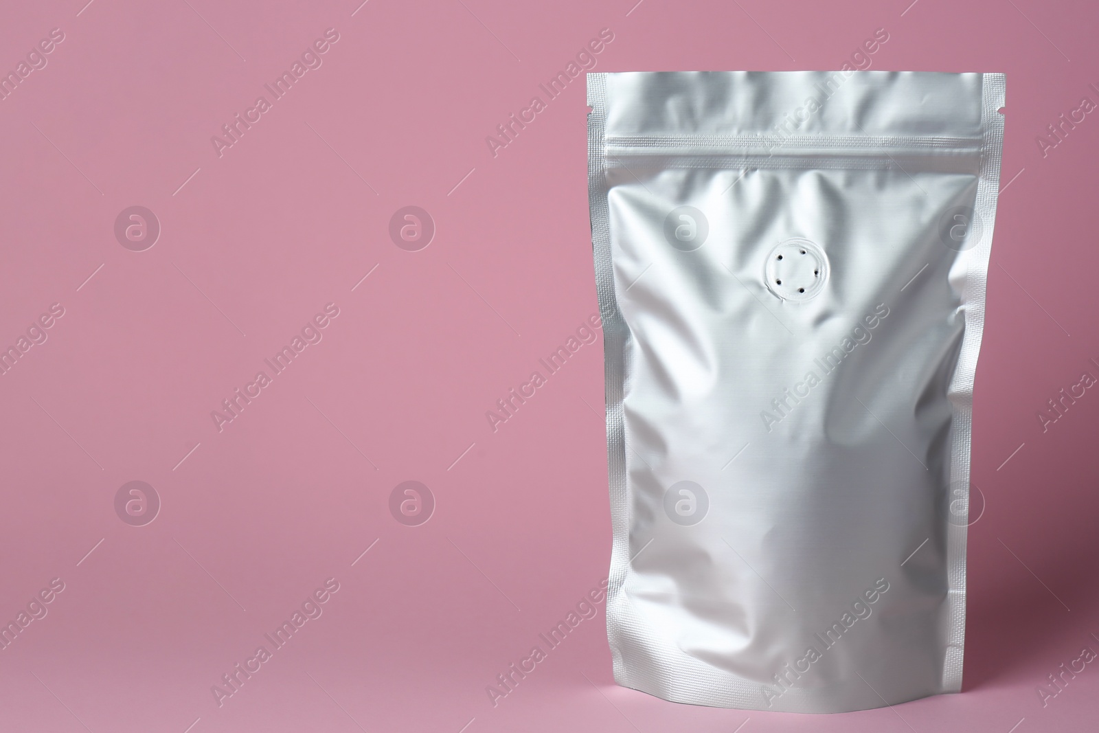 Photo of One blank foil package on pink background. Space for text