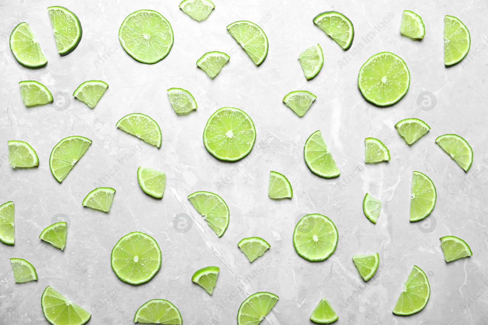 Photo of Slices of fresh juicy lime on marble table, flat lay