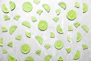 Photo of Slices of fresh juicy lime on marble table, flat lay