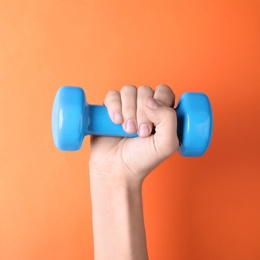 Photo of Woman holding vinyl dumbbell on color background, closeup