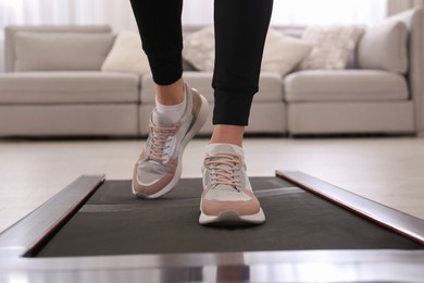 Woman training on walking treadmill at home, closeup