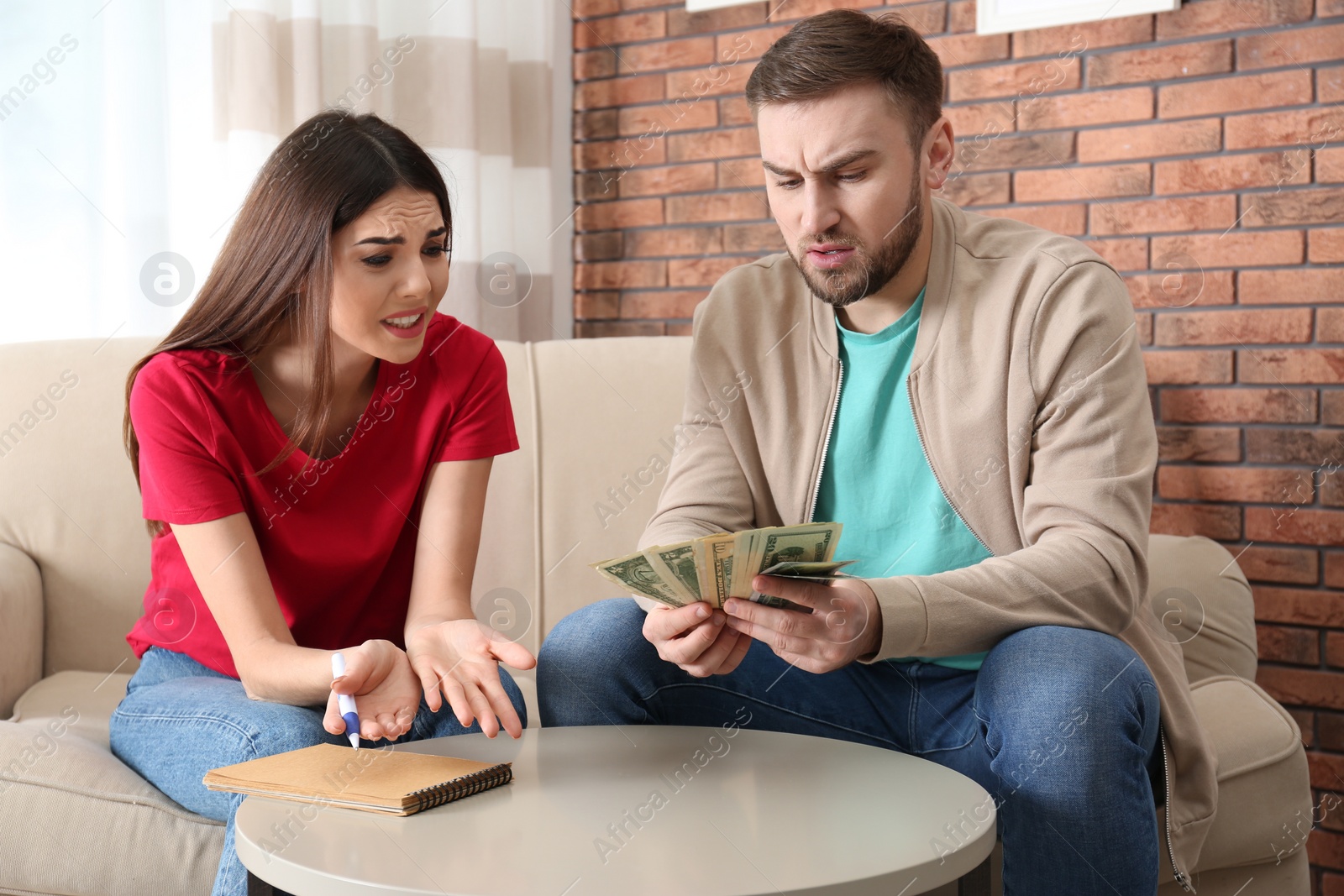 Photo of Unhappy young couple with money at home. Financial problems