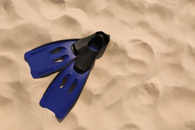 Photo of Pair of blue flippers on sand, top view. Space for text