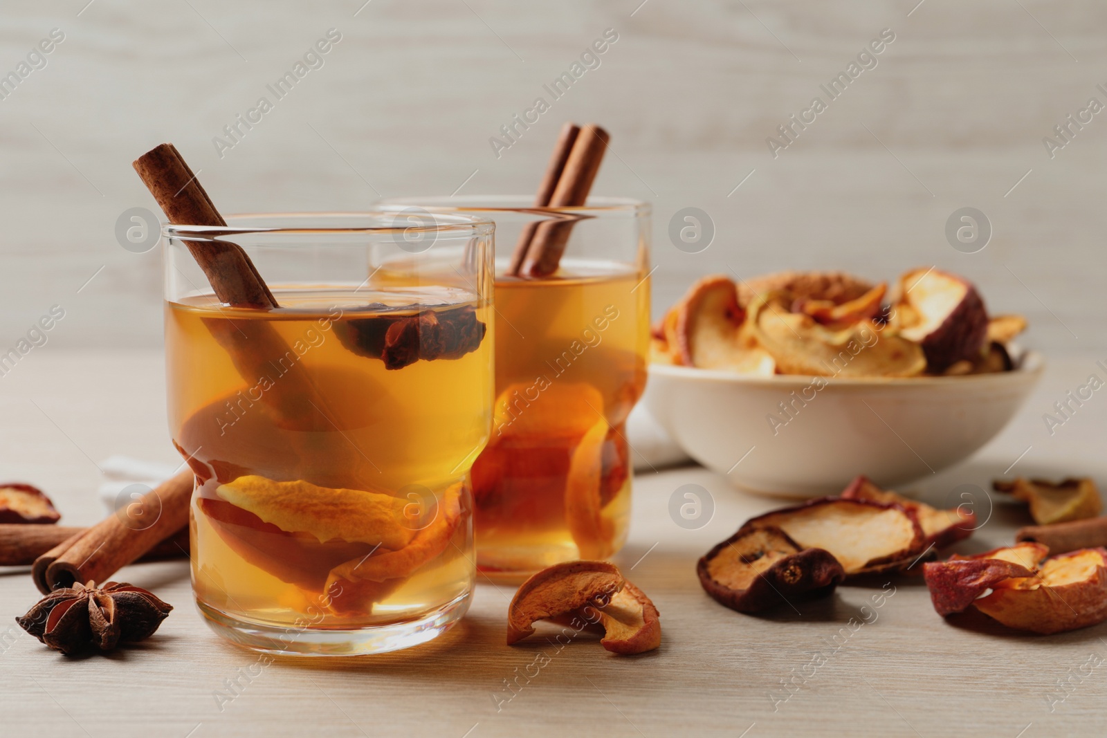 Photo of Delicious compote with dried apple slices, anise and cinnamon on white wooden table