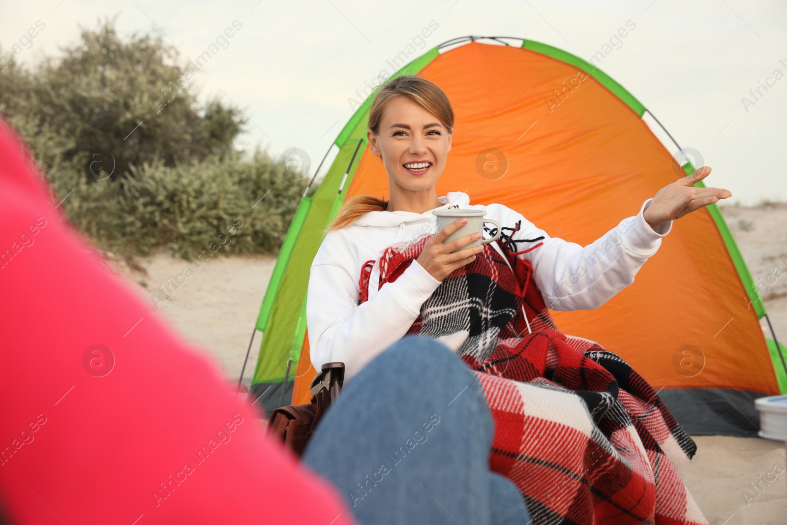 Photo of Friends resting near camping tent on sandy beach