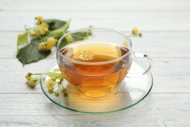 Cup of tea and linden blossom on white wooden table