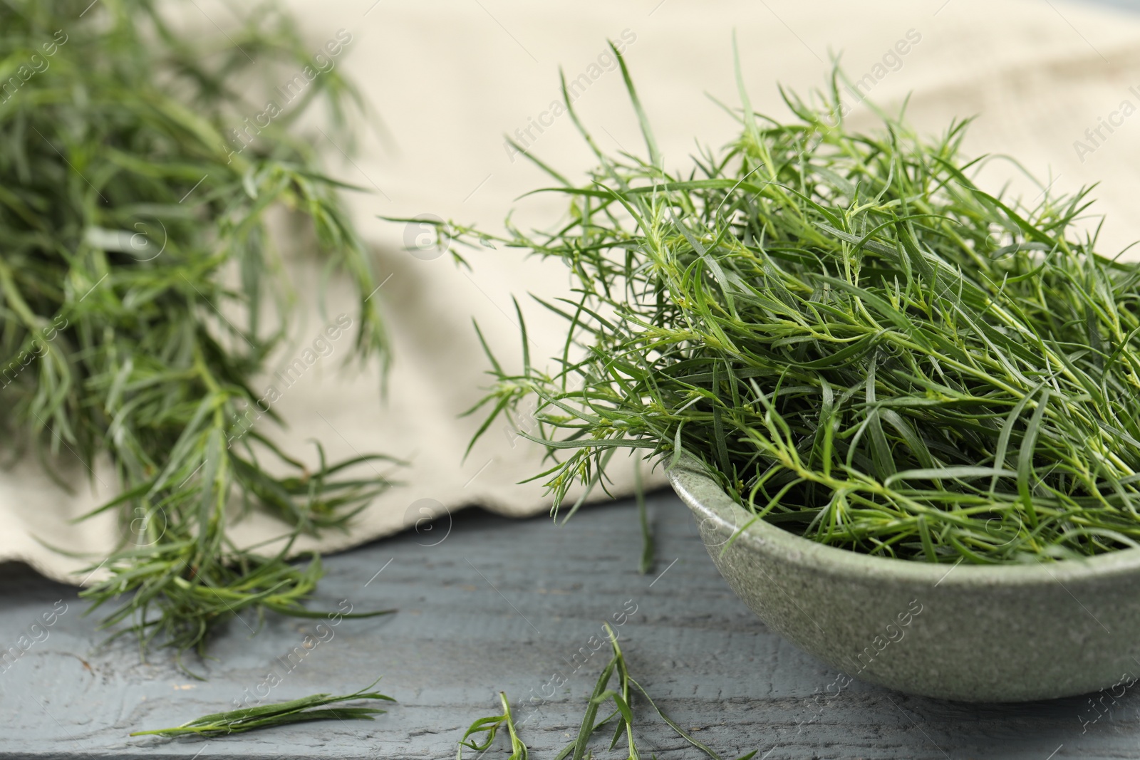 Photo of Fresh tarragon leaves on grey wooden table, closeup
