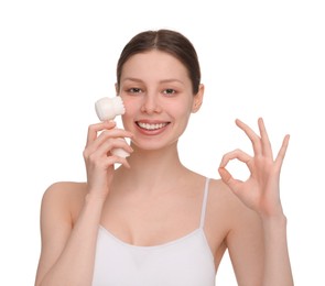 Photo of Washing face. Young woman with cleansing brush showing OK gesture on white background