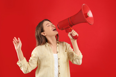 Photo of Young woman with megaphone on red background