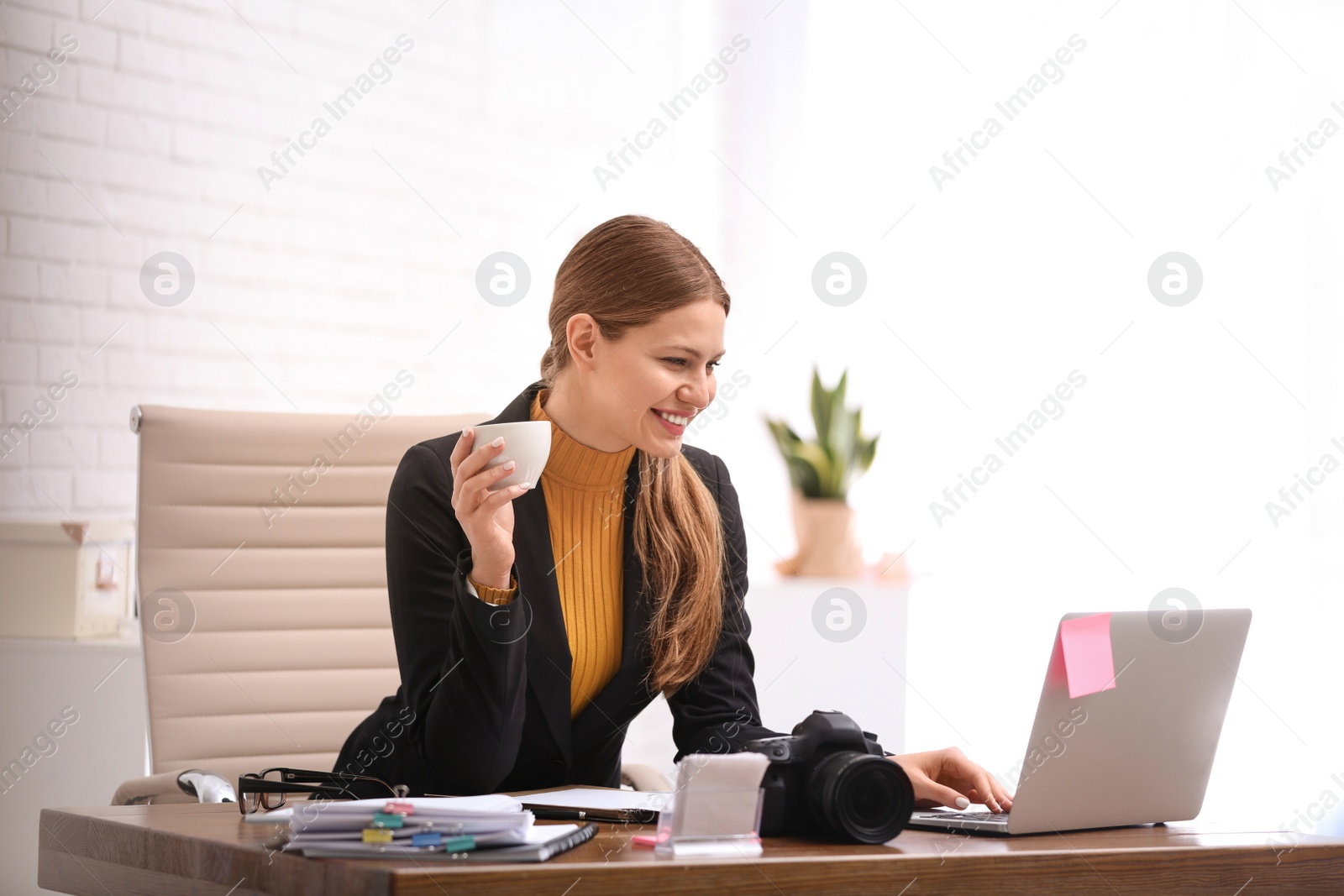 Photo of Journalist with coffee working at table in office