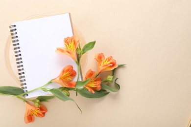 Guest list. Notebook and beautiful flowers on beige background, top view. Space for text
