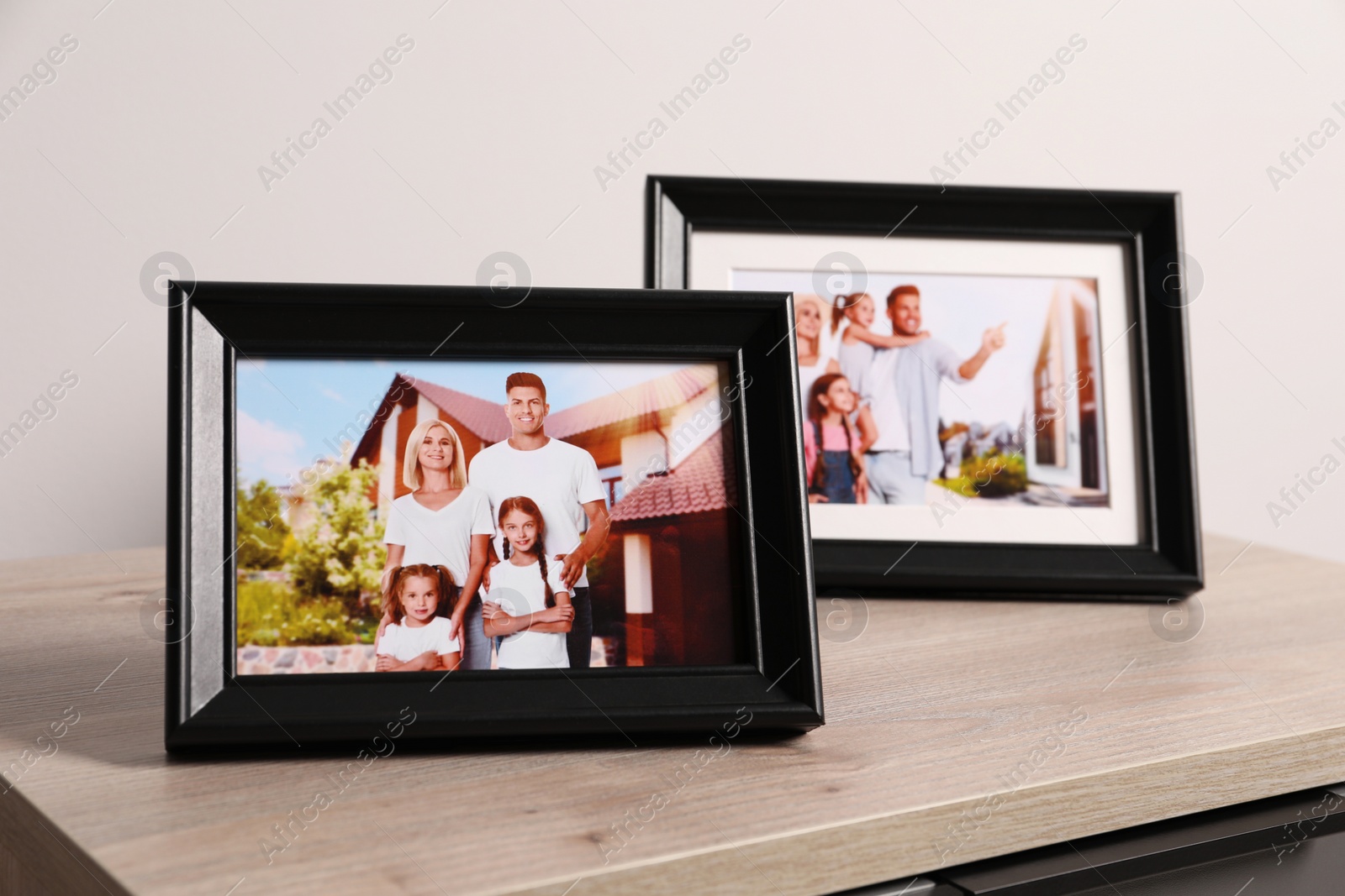 Photo of Frames with family photos on wooden table near white wall