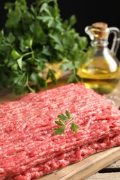 Raw ground meat, parsley and oil on table