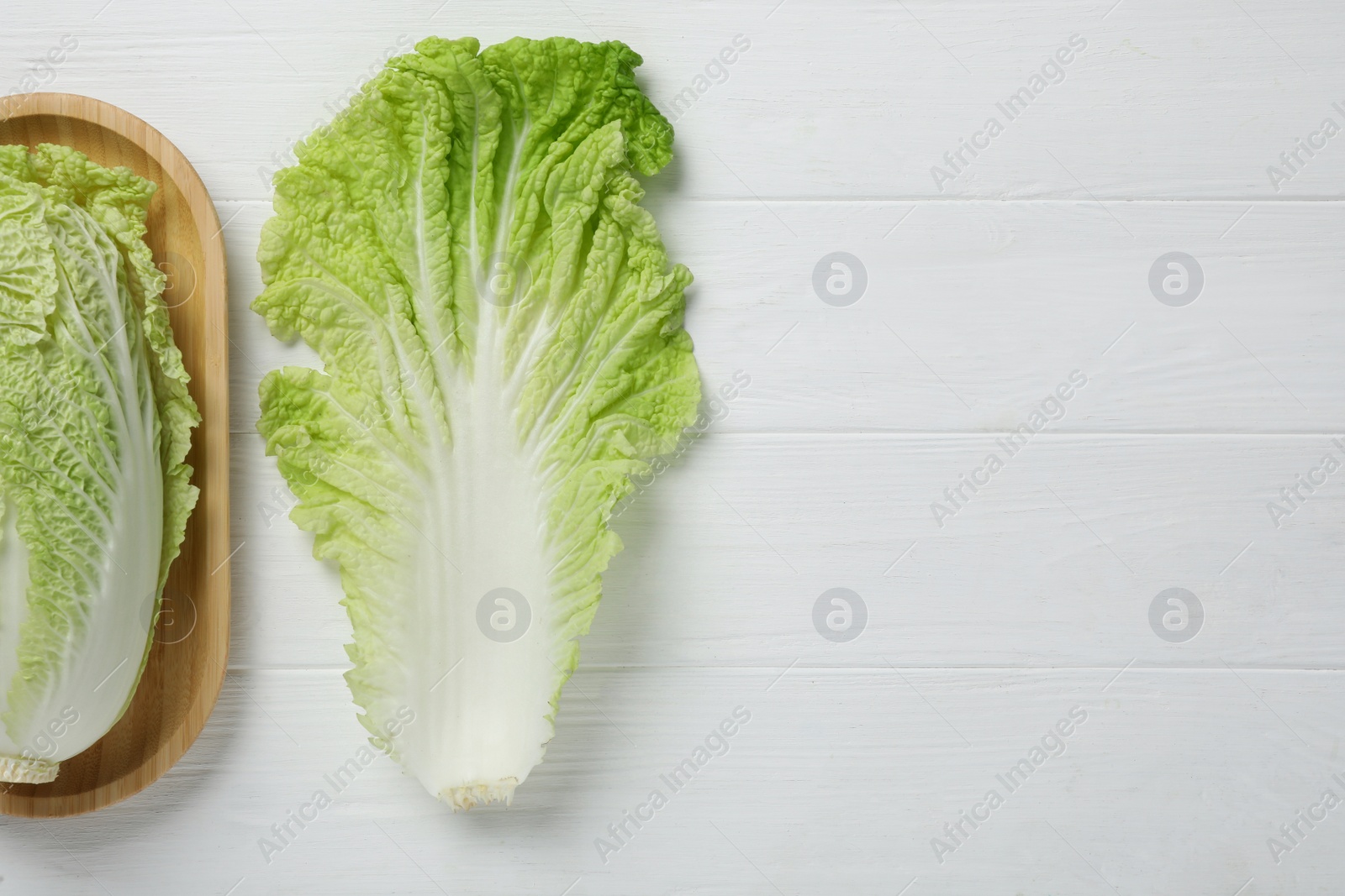 Photo of Fresh ripe Chinese cabbage and leaf on white wooden table, flat lay. Space for text