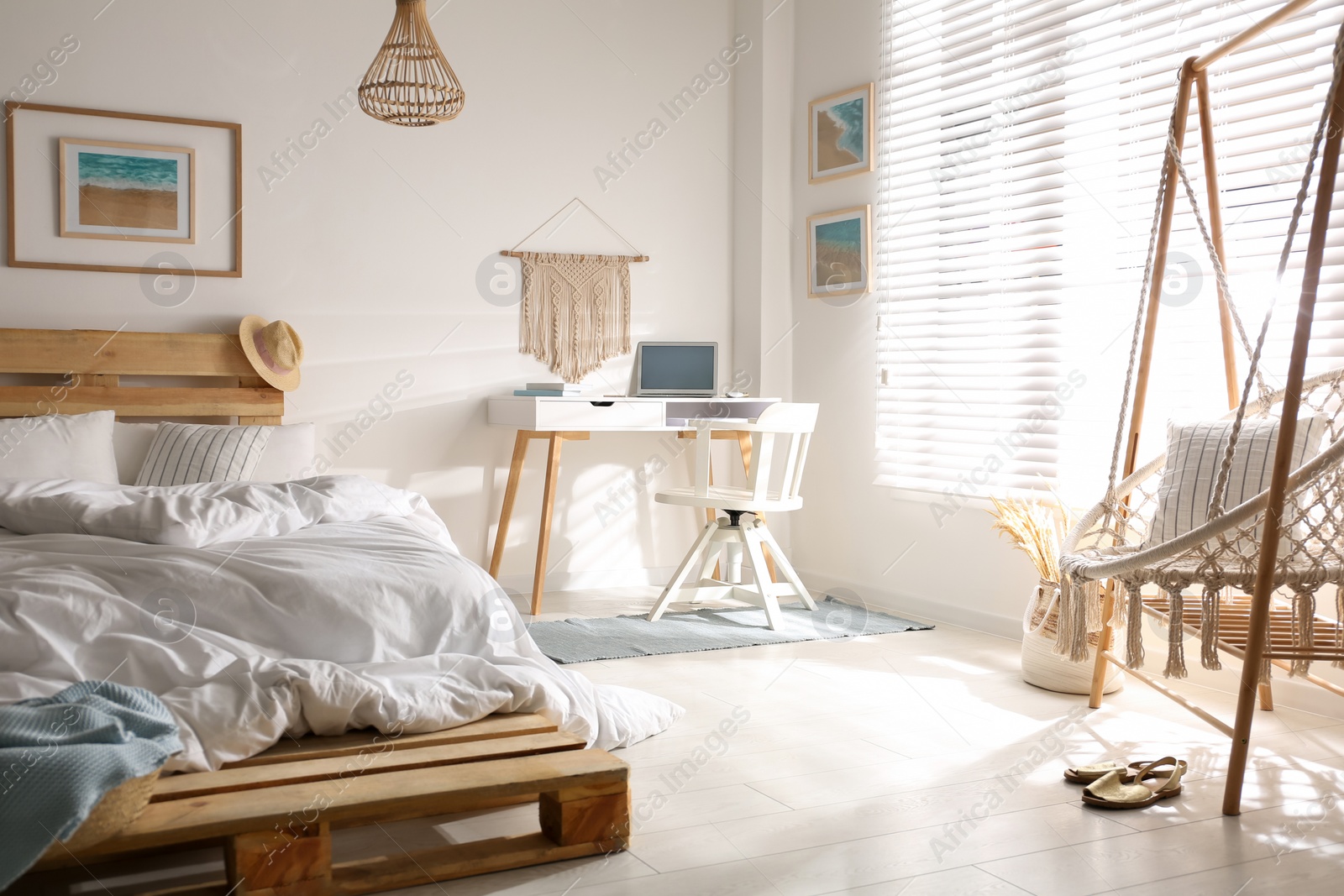 Photo of Stylish room interior with workplace, hanging chair and bed