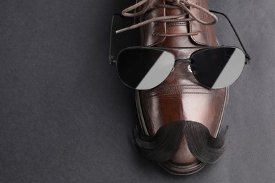 Photo of Artificial moustache, shoe and sunglasses on black background, top view. Space for text