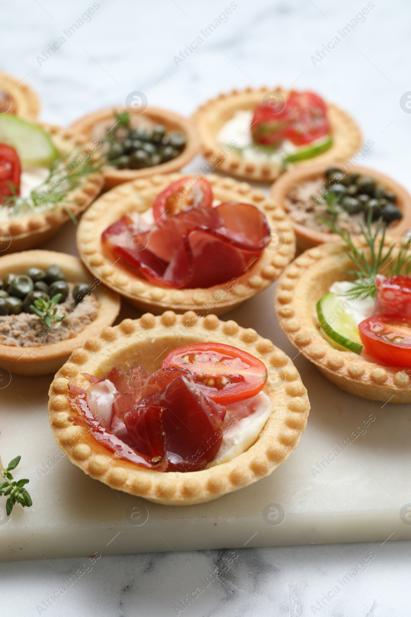 Photo of Different delicious canapes on white marble table, closeup