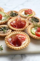 Different delicious canapes on white marble table, closeup