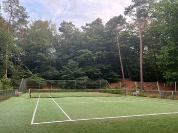 Photo of Tennis court with green grass and net outdoors