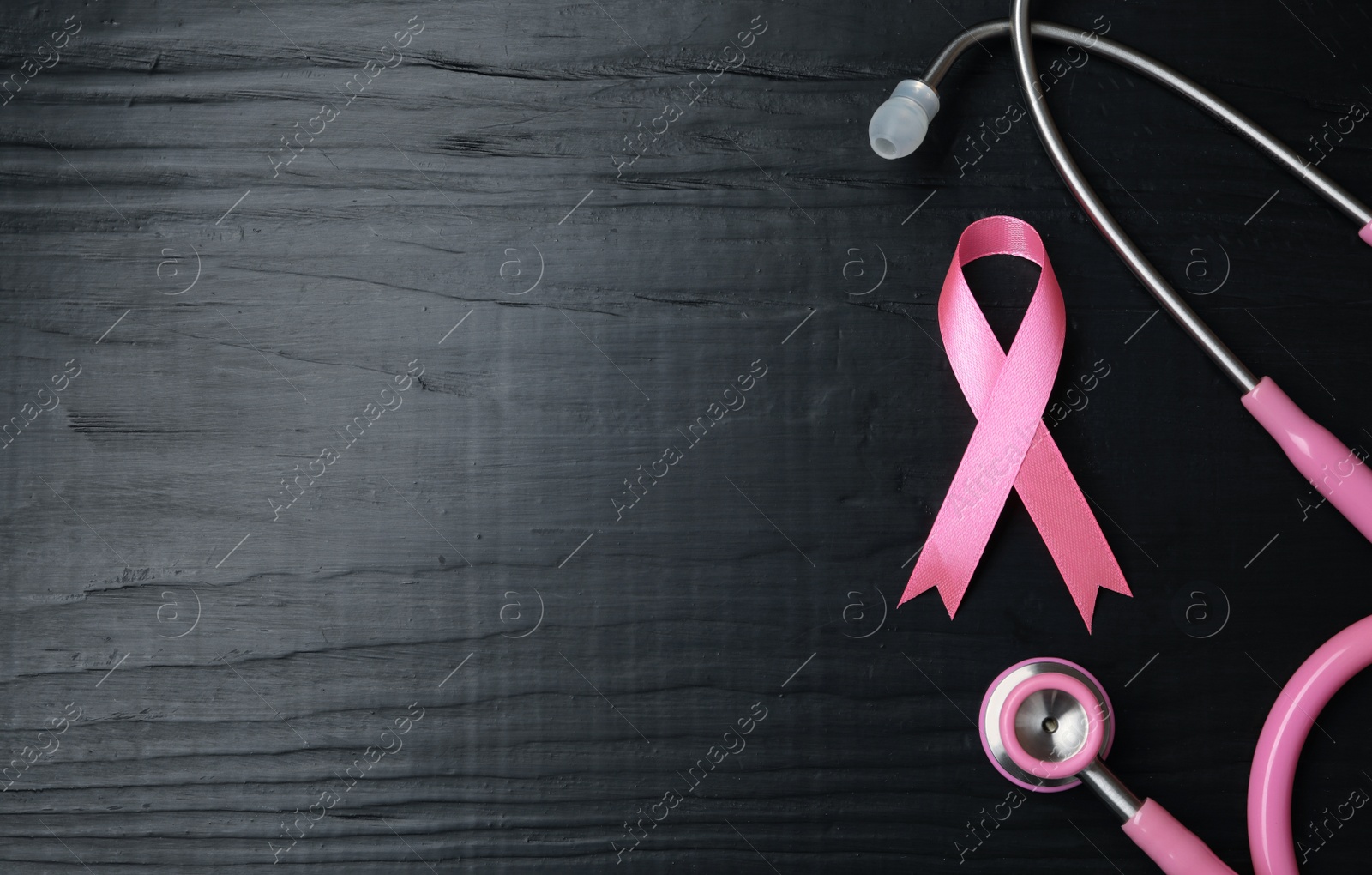 Photo of Pink ribbon and stethoscope on wooden background, top view with space for text. Breast cancer concept