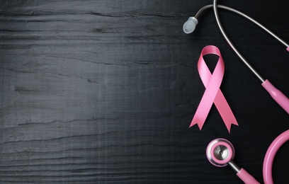 Pink ribbon and stethoscope on wooden background, top view with space for text. Breast cancer concept