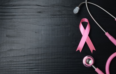 Photo of Pink ribbon and stethoscope on wooden background, top view with space for text. Breast cancer concept