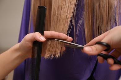 Photo of Stylist cutting hair of client in professional salon, closeup