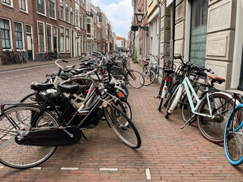 Many different bicycles parked near building on city street