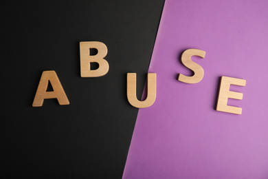 Photo of Word ABUSE on color background, flat lay. Domestic violence awareness