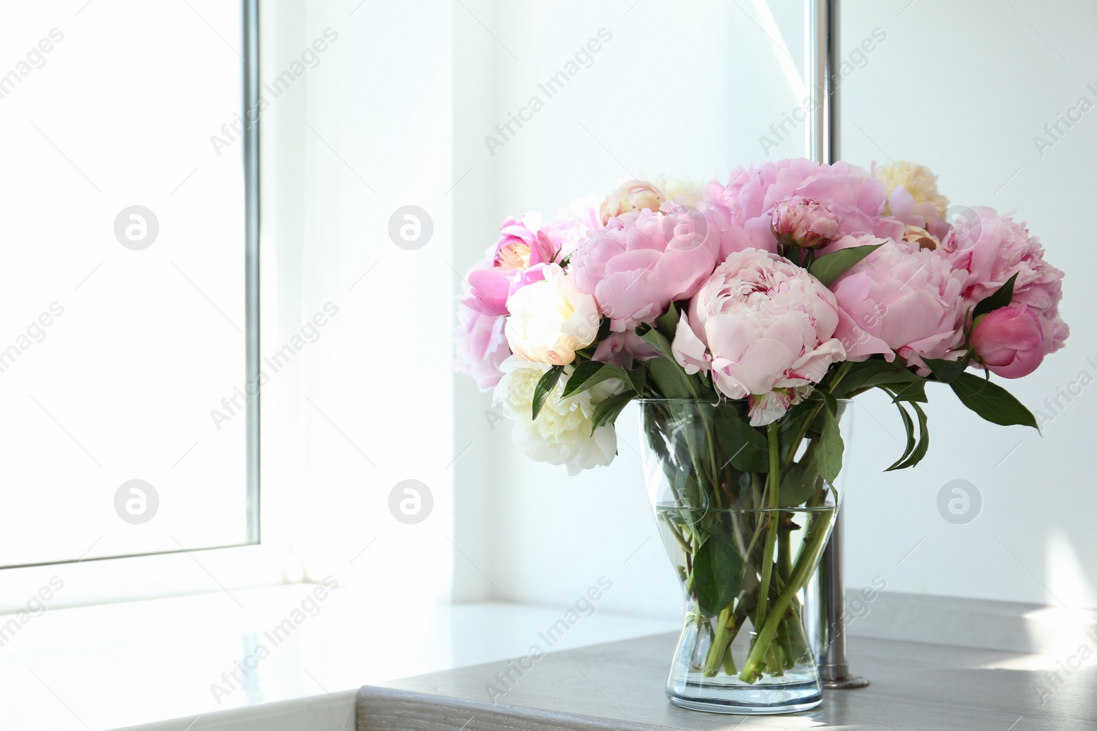 Photo of Bouquet of beautiful peonies in vase on wooden table. Space for text