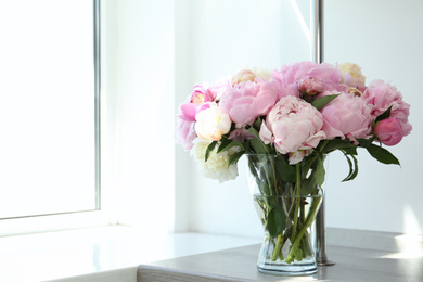 Photo of Bouquet of beautiful peonies in vase on wooden table. Space for text