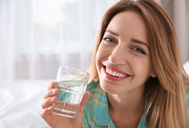 Photo of Young woman with glass of clean water at home