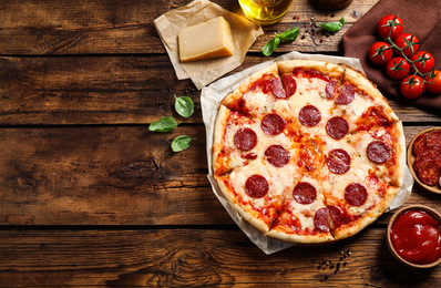 Photo of Flat lay composition with hot pepperoni pizza on wooden table. Space for text
