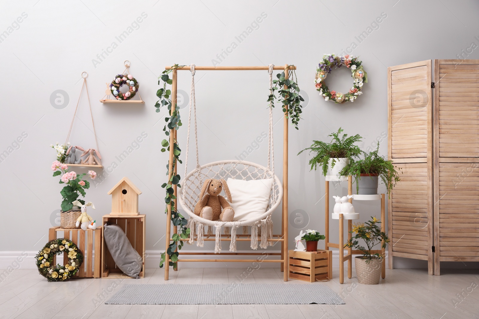 Photo of Easter photo zone with floral decor and swing chair indoors