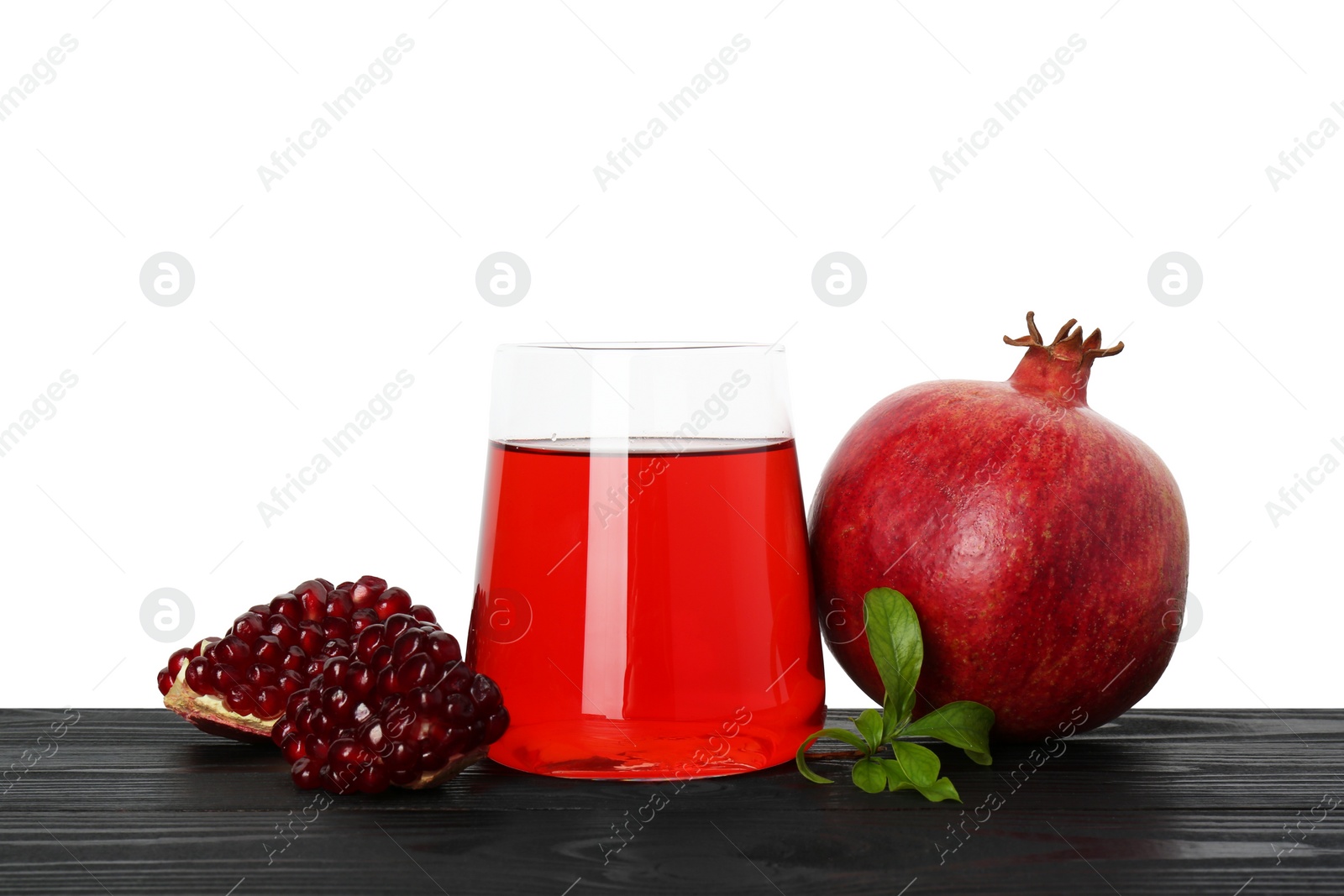 Photo of Refreshing pomegranate juice in glass, leaves and fruits on black wooden table against white background