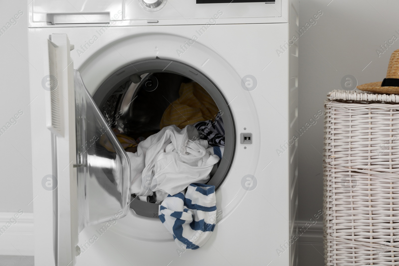 Photo of Washing machine with laundry near wall in room