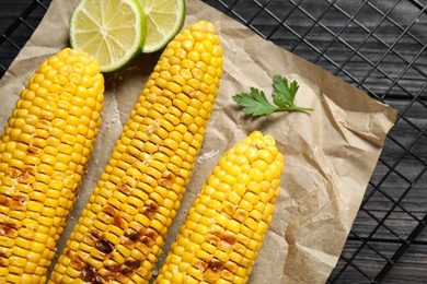 Photo of Tasty grilled corn on wooden table, flat lay