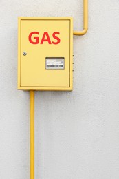 Photo of Gas meter box and pipes near grey wall outdoors