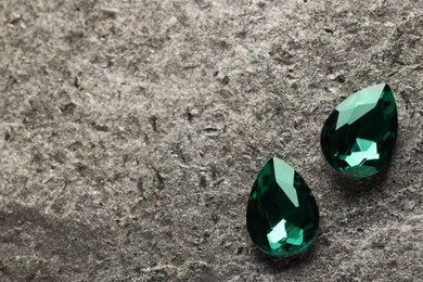 Photo of Beautiful green gemstones for jewelry on stone surface, above view. Space for text