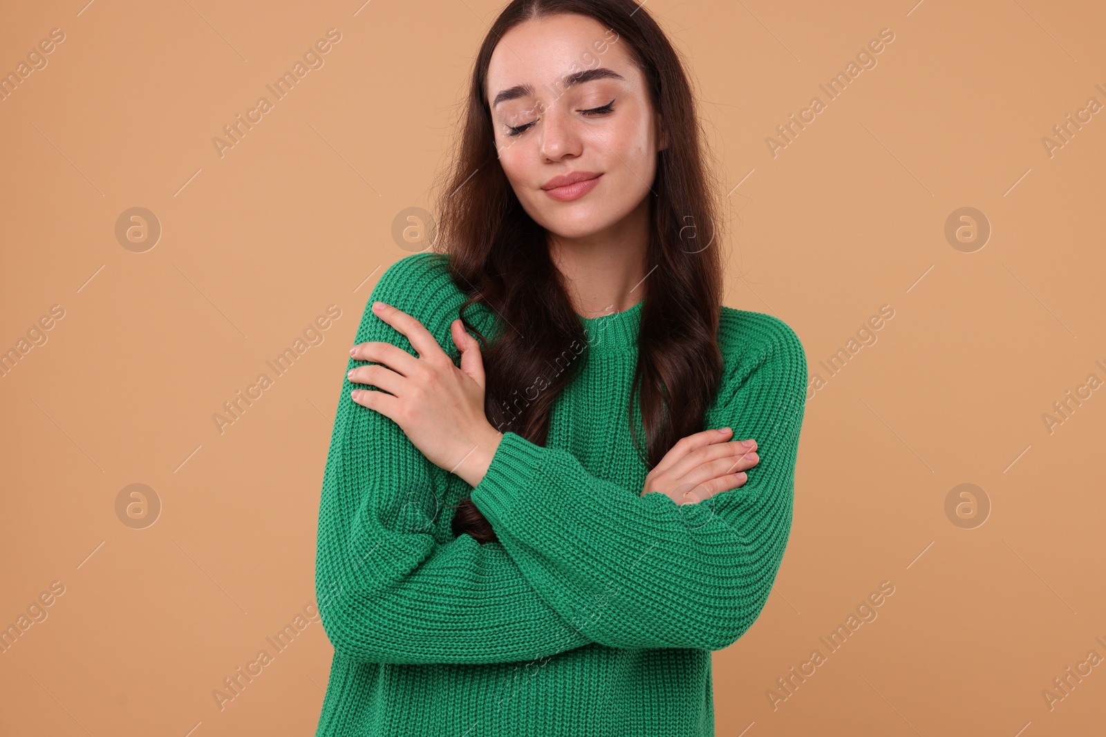 Photo of Beautiful young woman in stylish warm sweater on beige background